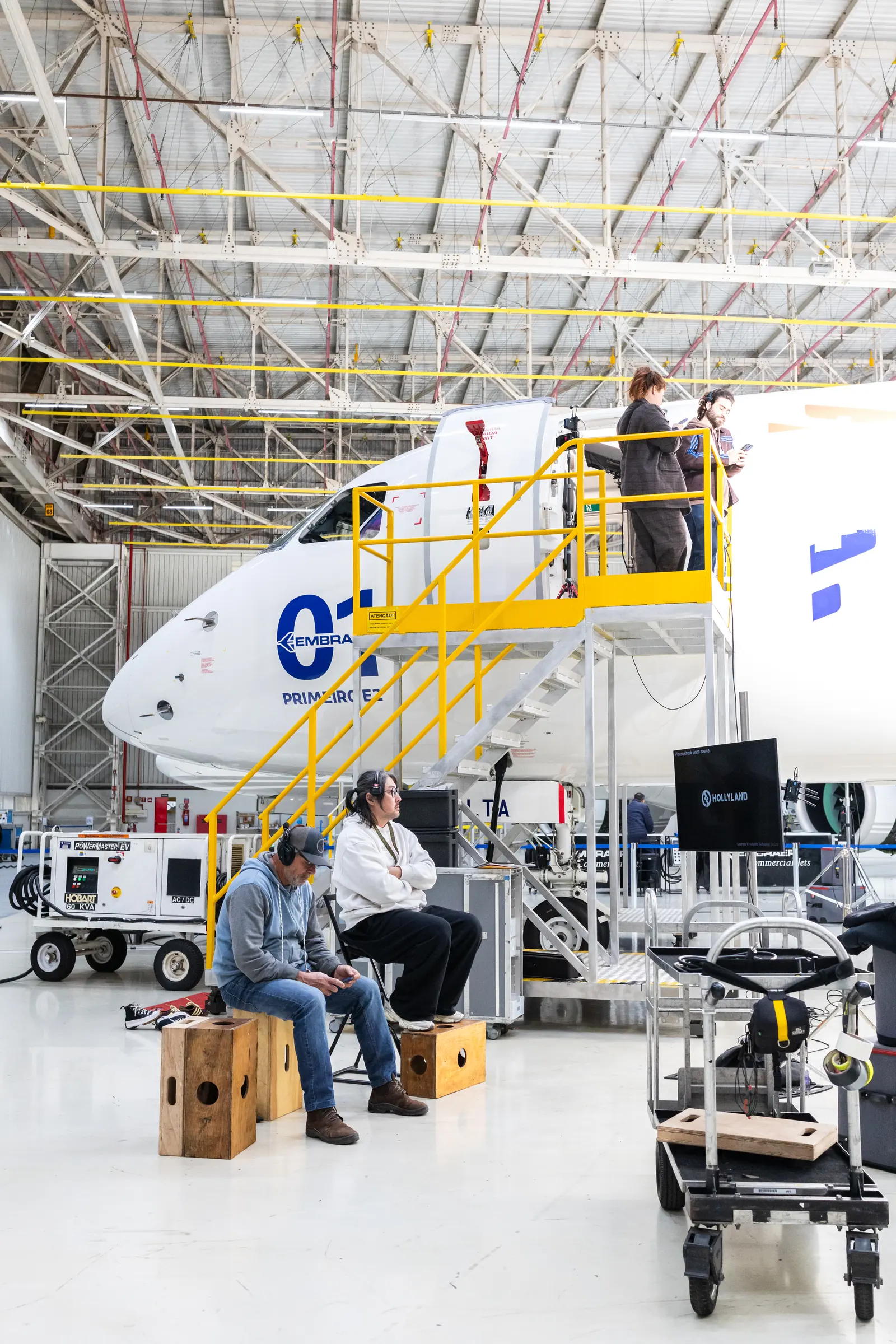 Two crew members seated by the nose of the aircraft between setups
